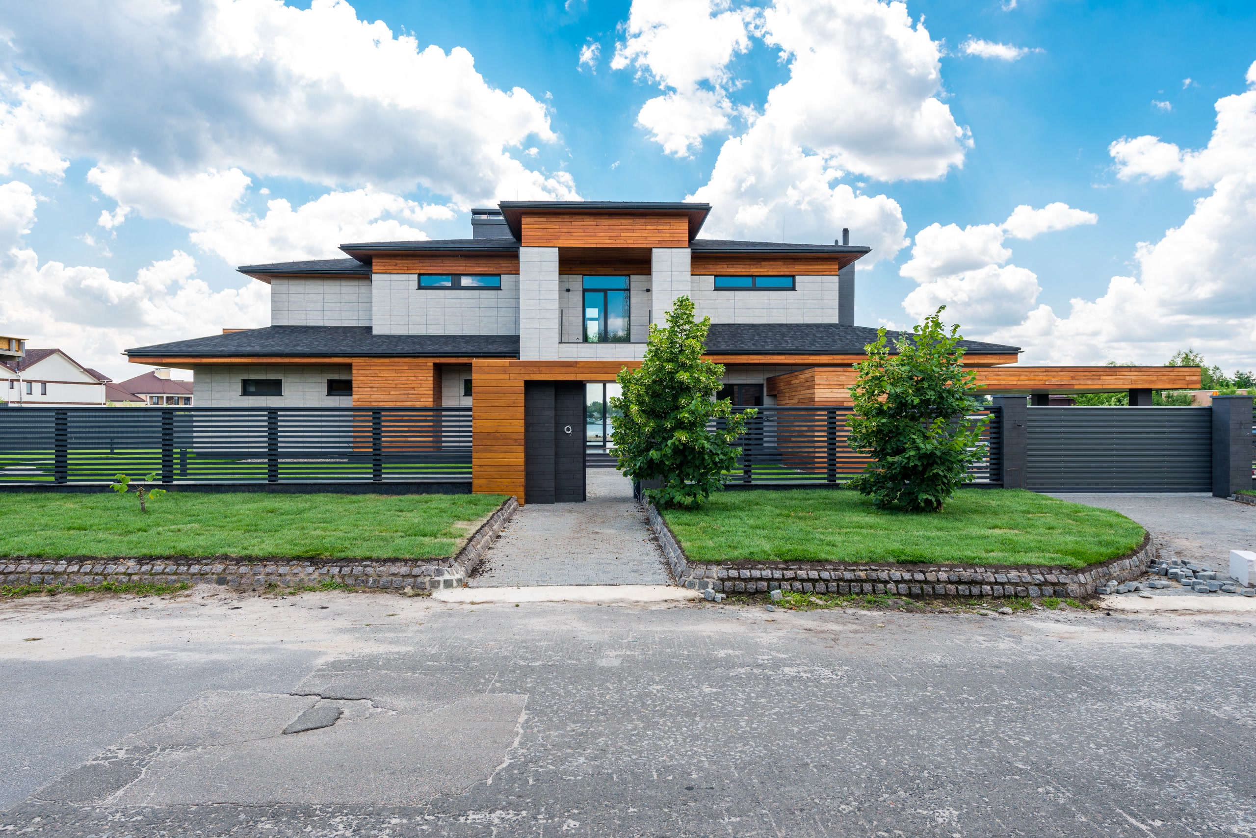 Street view of a modern home behind a slatted fence