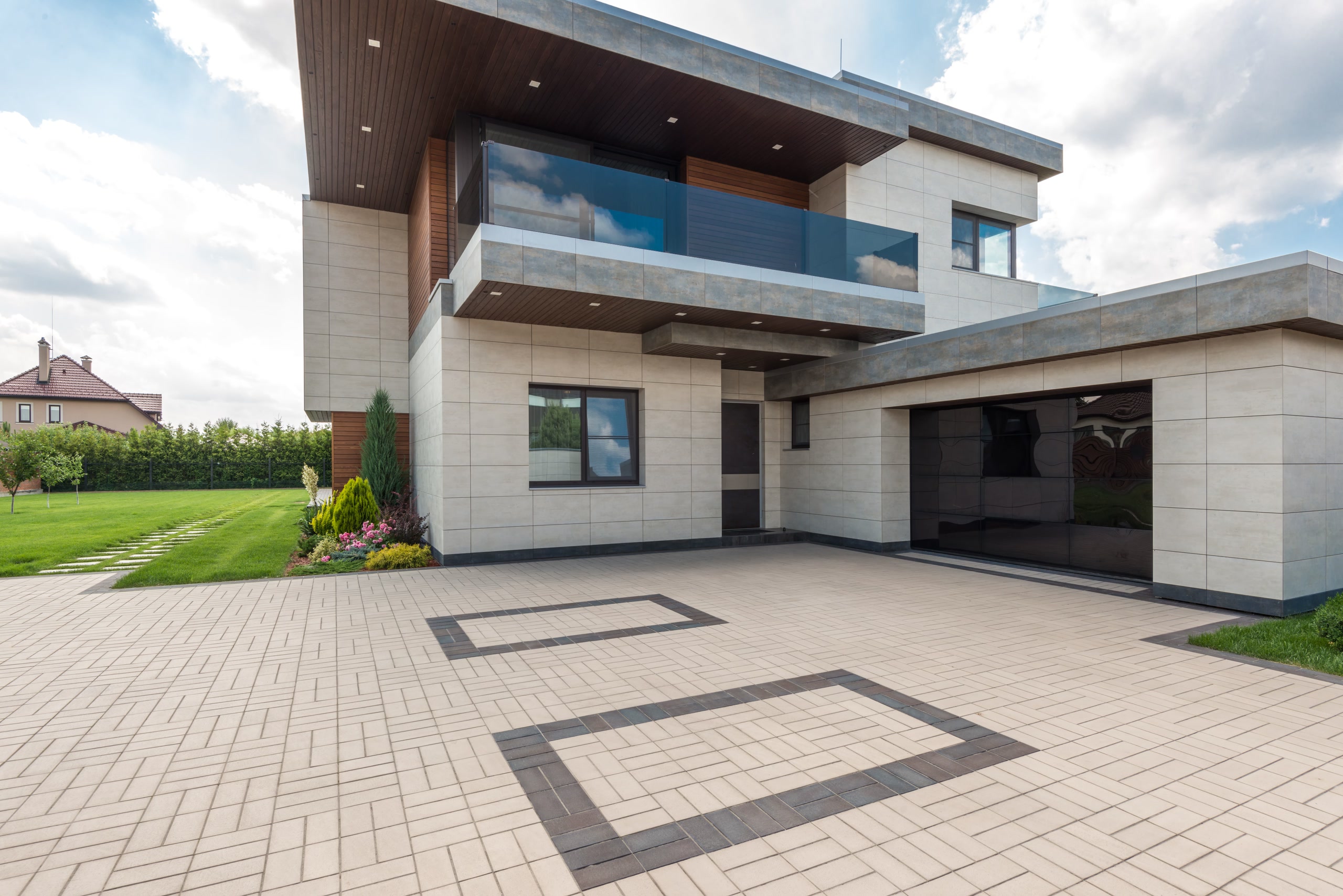 Stone-clad home with glass balcony and paved courtyard