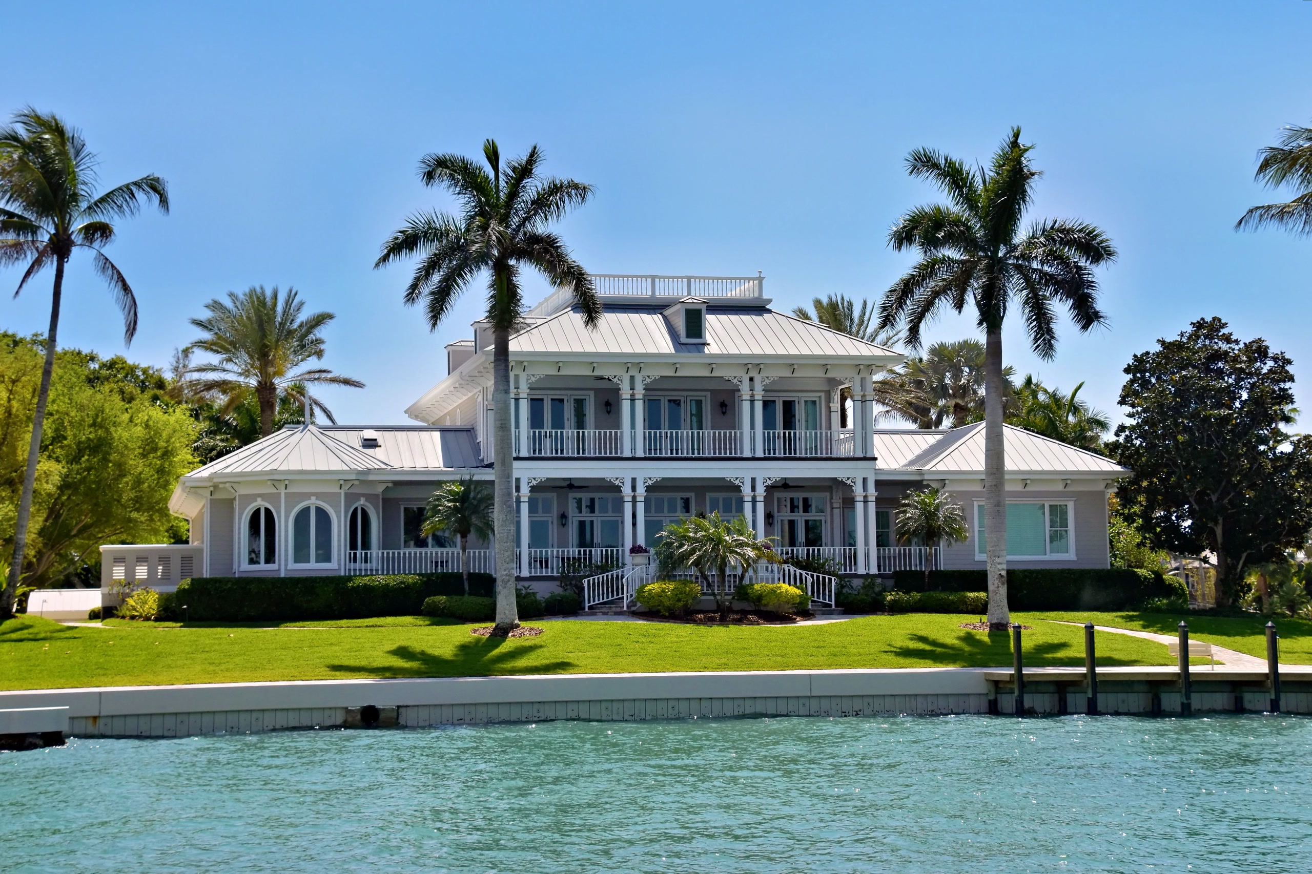 Waterfront home with palms and wraparound porch